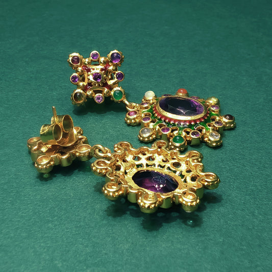 Gold earrings with gemstones on a green background