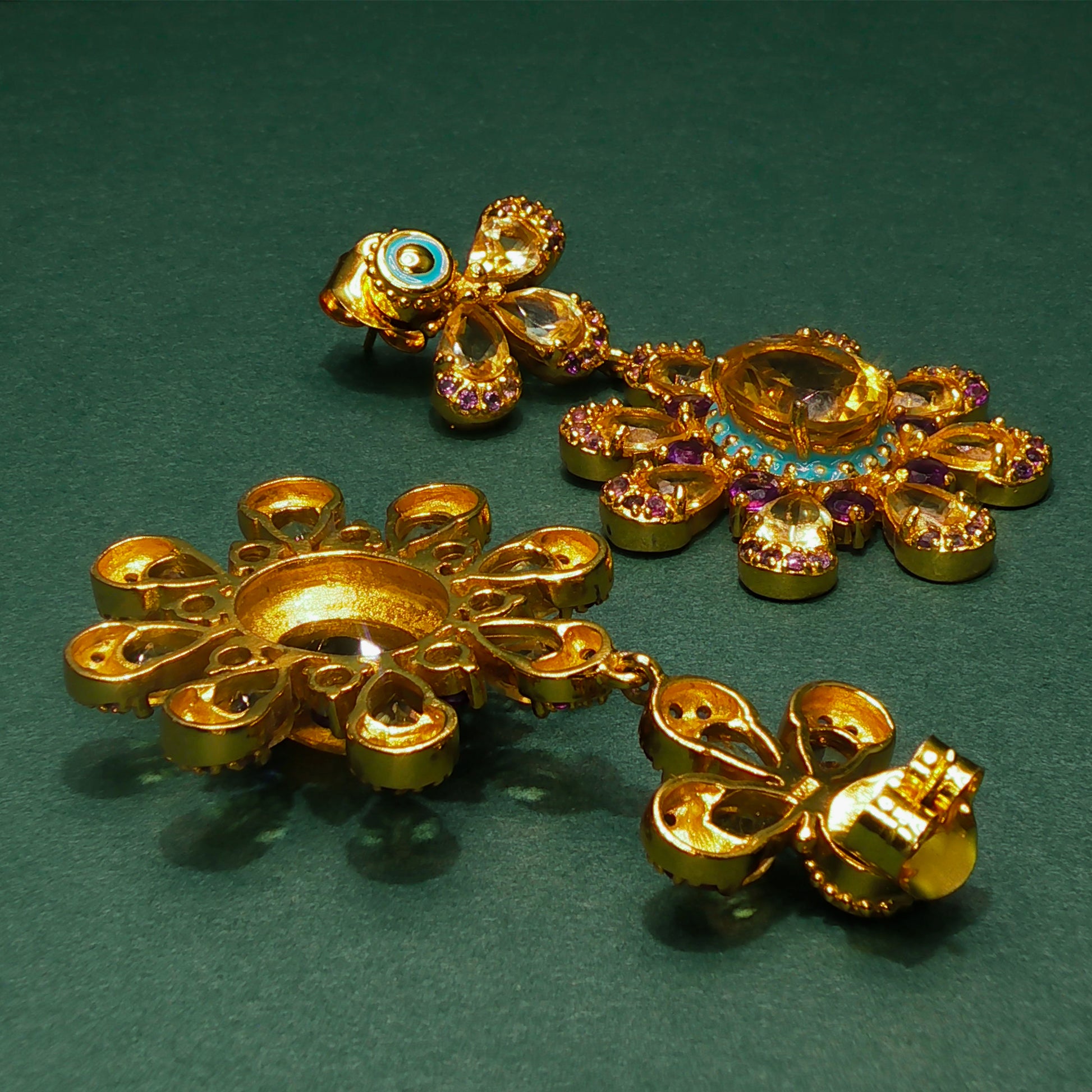 Gold earrings with gemstones on a green background