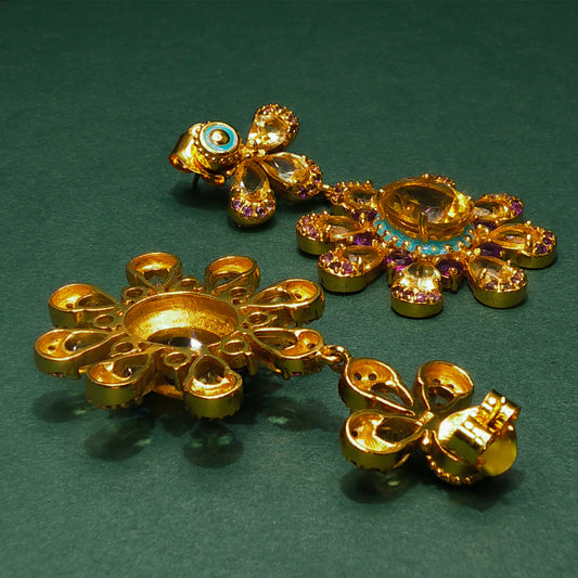 Gold earrings with gemstones on a green background