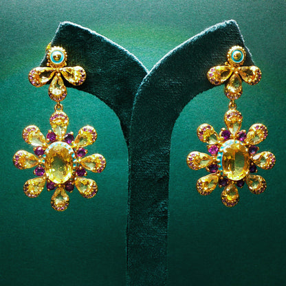 Gold earrings with gemstones on green earring stands