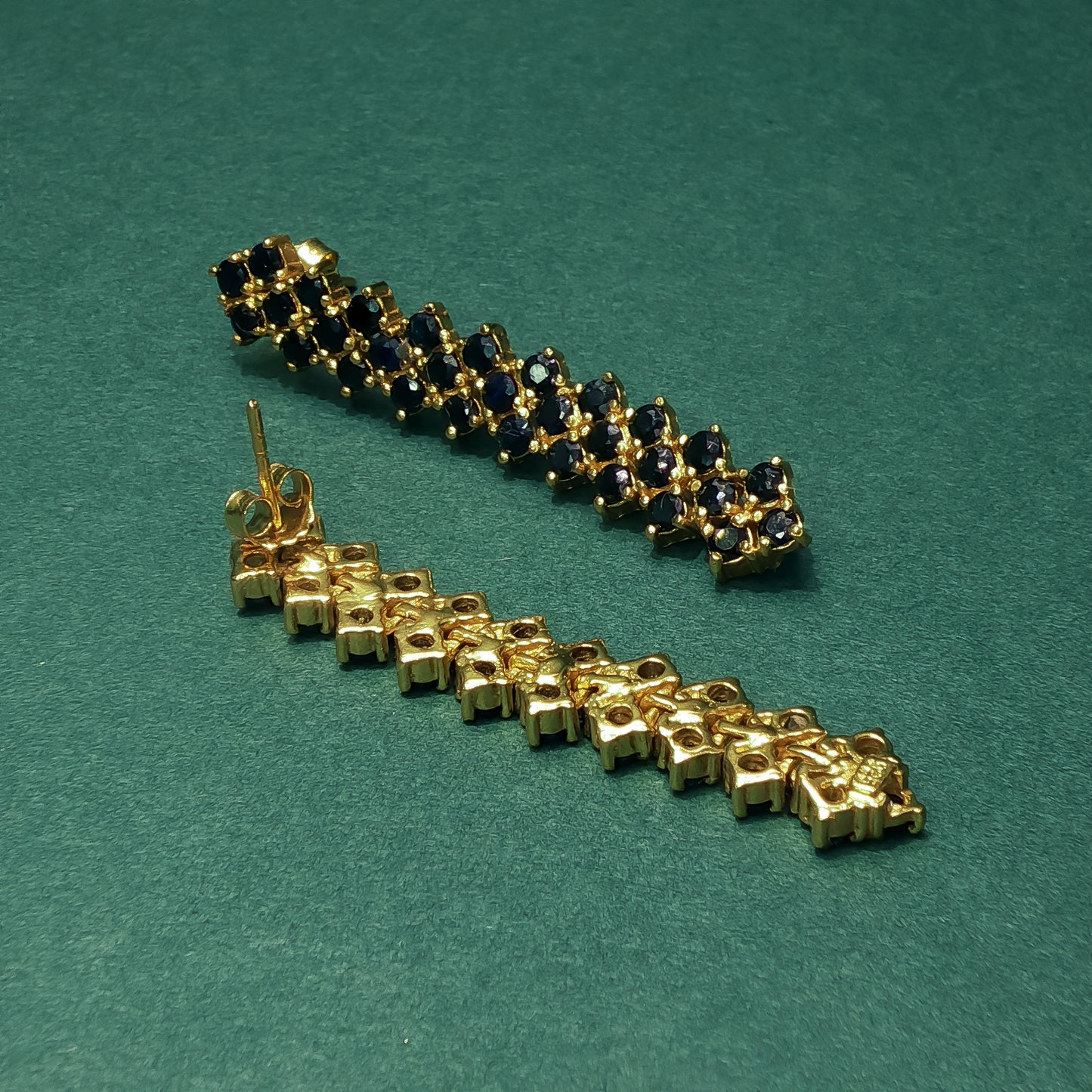 Gold and blue gemstone bracelet on a green background