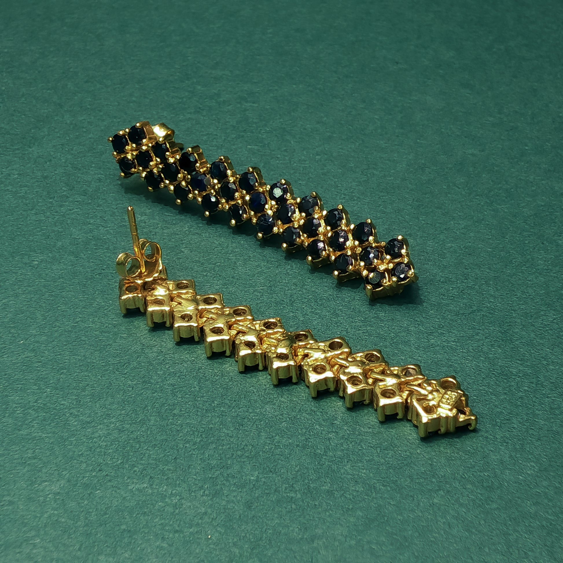 Gold and blue gemstone bracelet on a green background