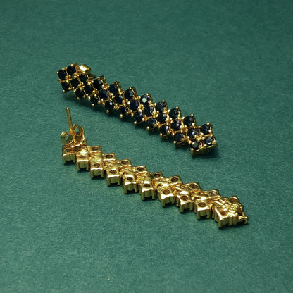 Gold and blue gemstone bracelet on a green background