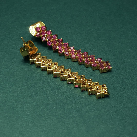 Gold and pink gemstone earring on a green background

