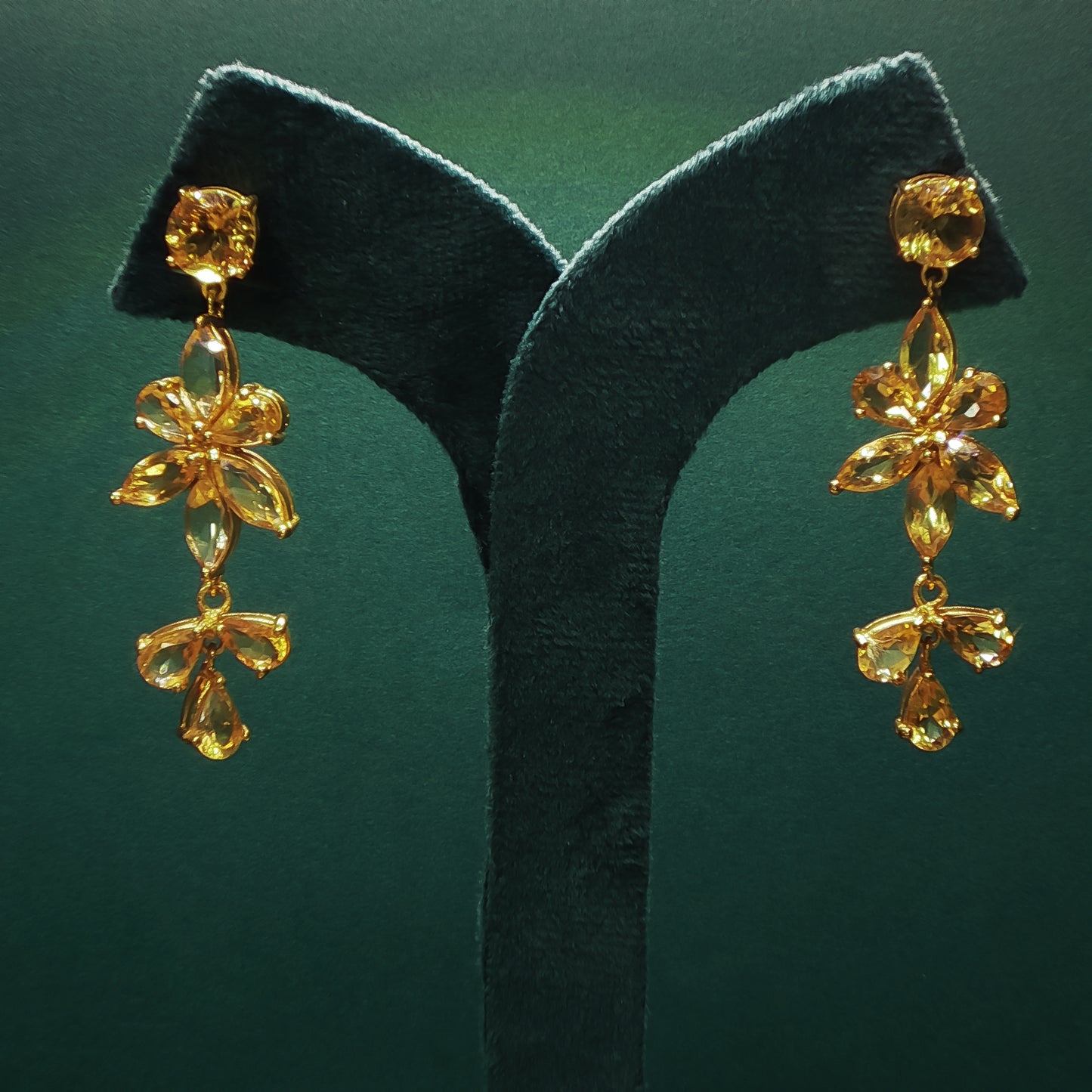 Gold earrings on a green leaf against a green background

