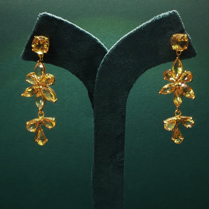 Gold earrings on a green leaf against a green background

