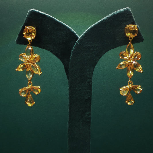 Gold earrings on a green leaf against a green background

