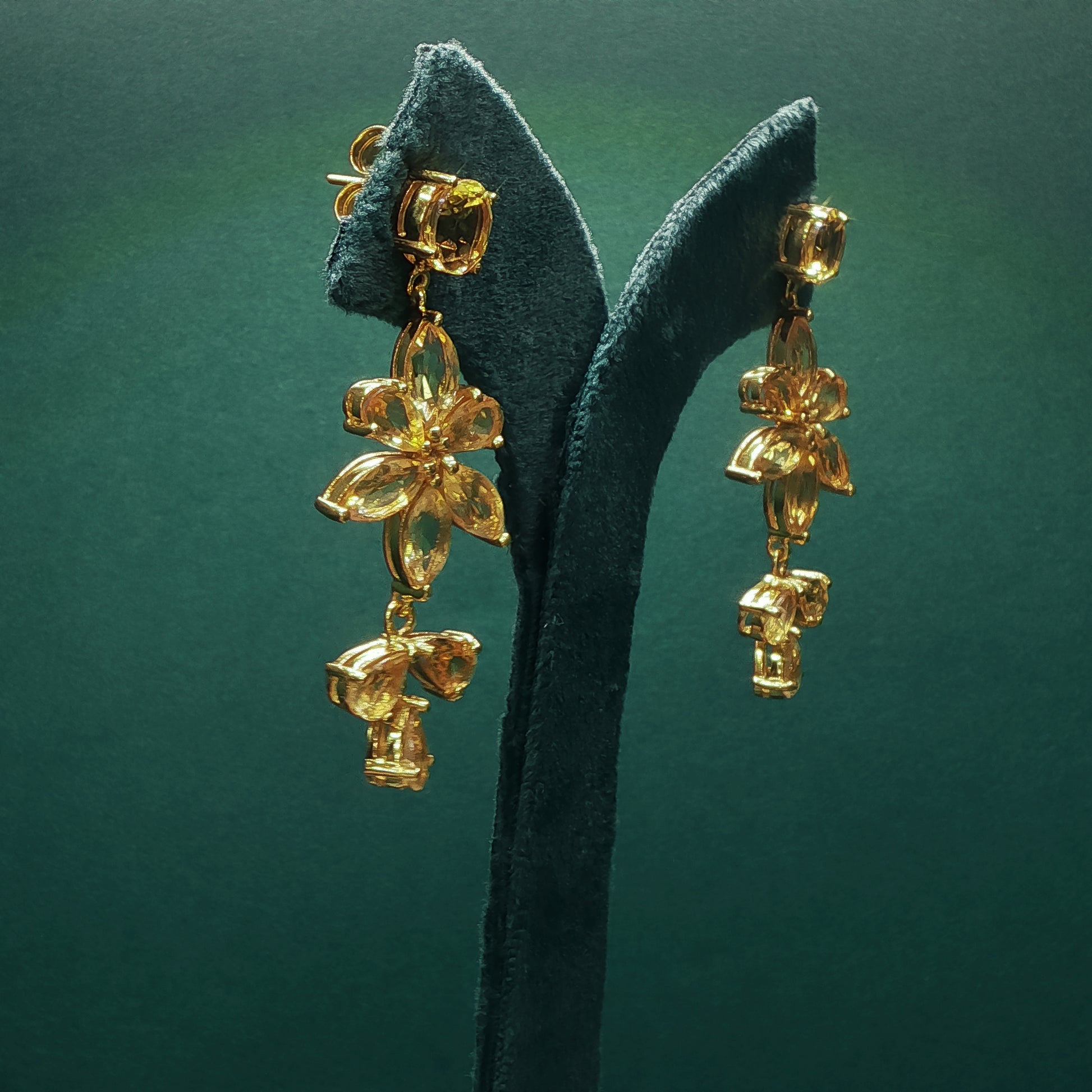 Gold earrings on a green leaf against a green background

