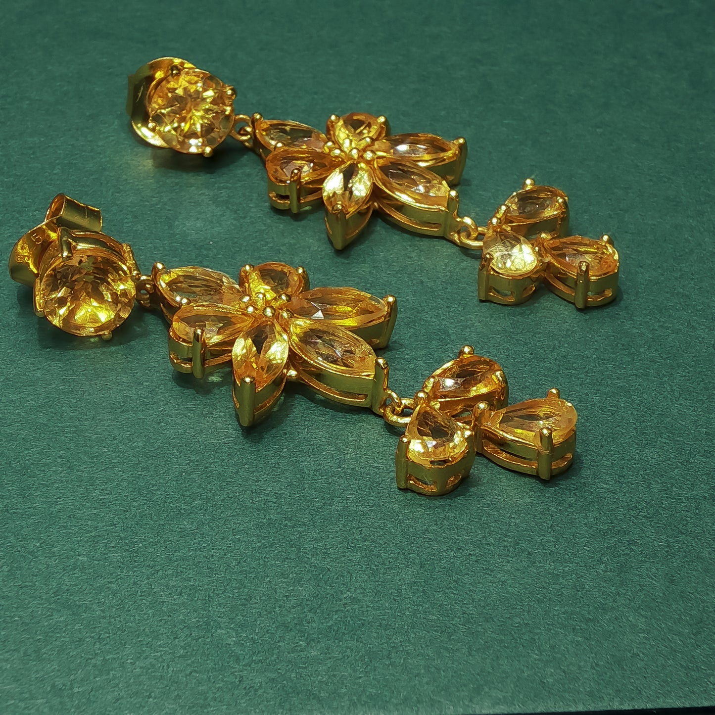 Gold bracelet with leaf and bow designs on a green background


