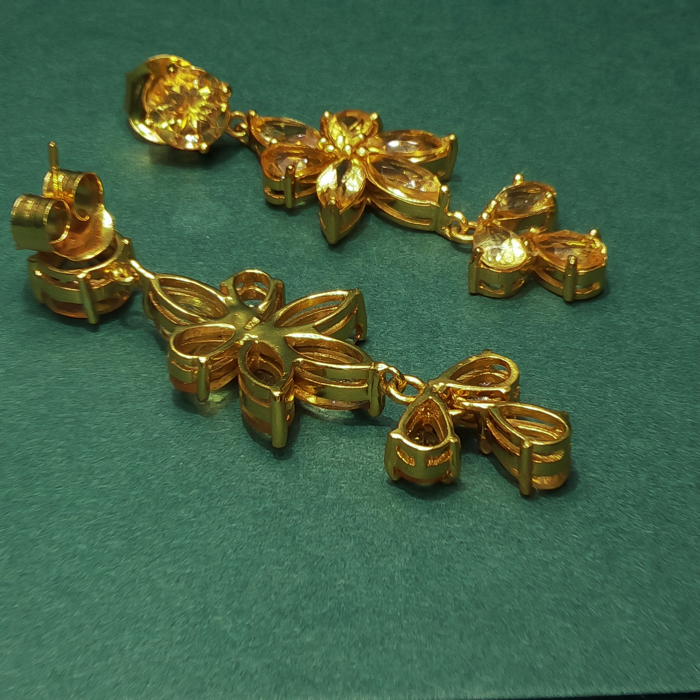 Gold bracelet with leaf and bow designs on a green background

