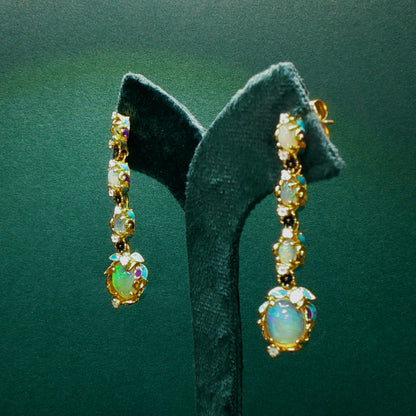 Gold earrings with opal stones on a green velvet stand

