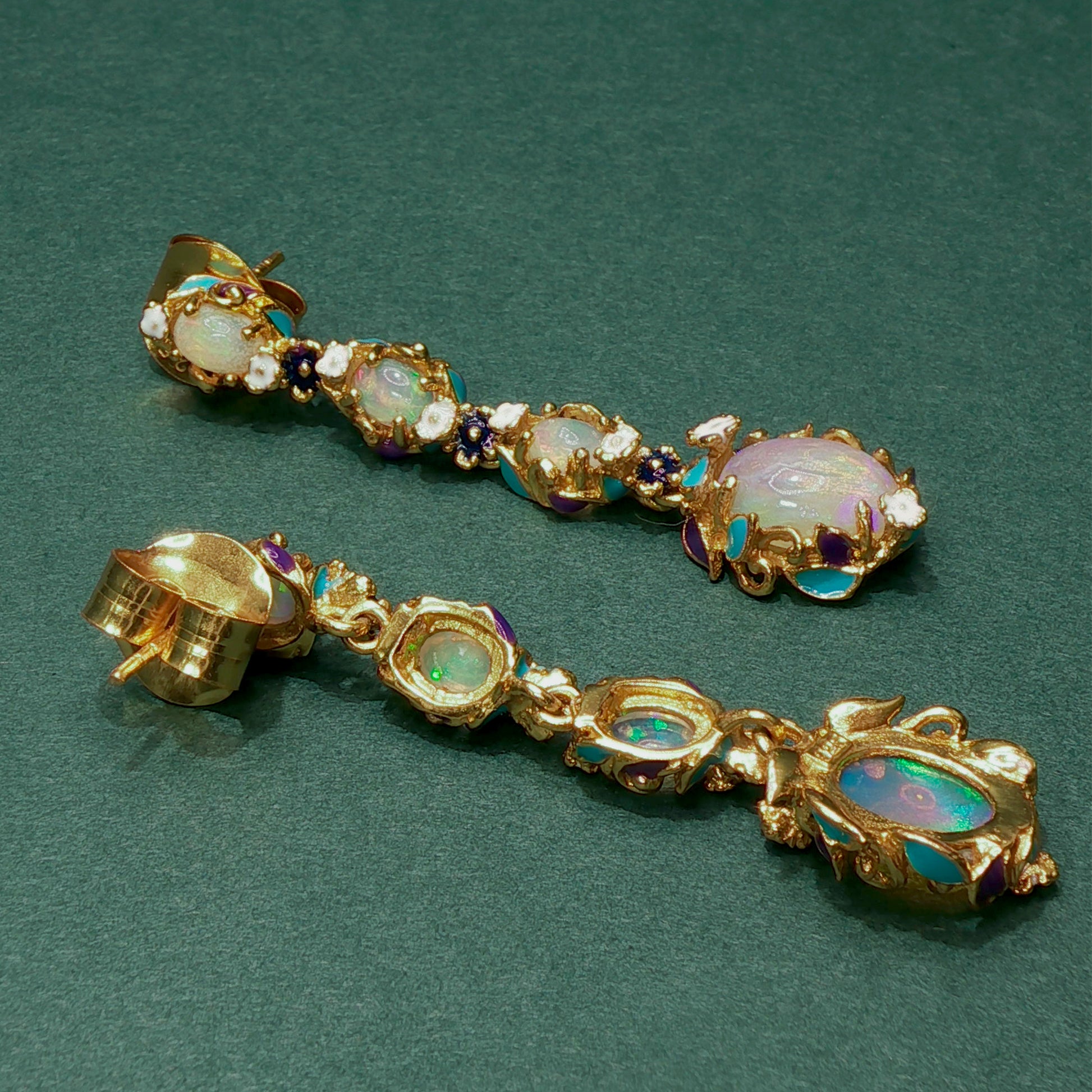 Gold earrings with gemstones on a green background

