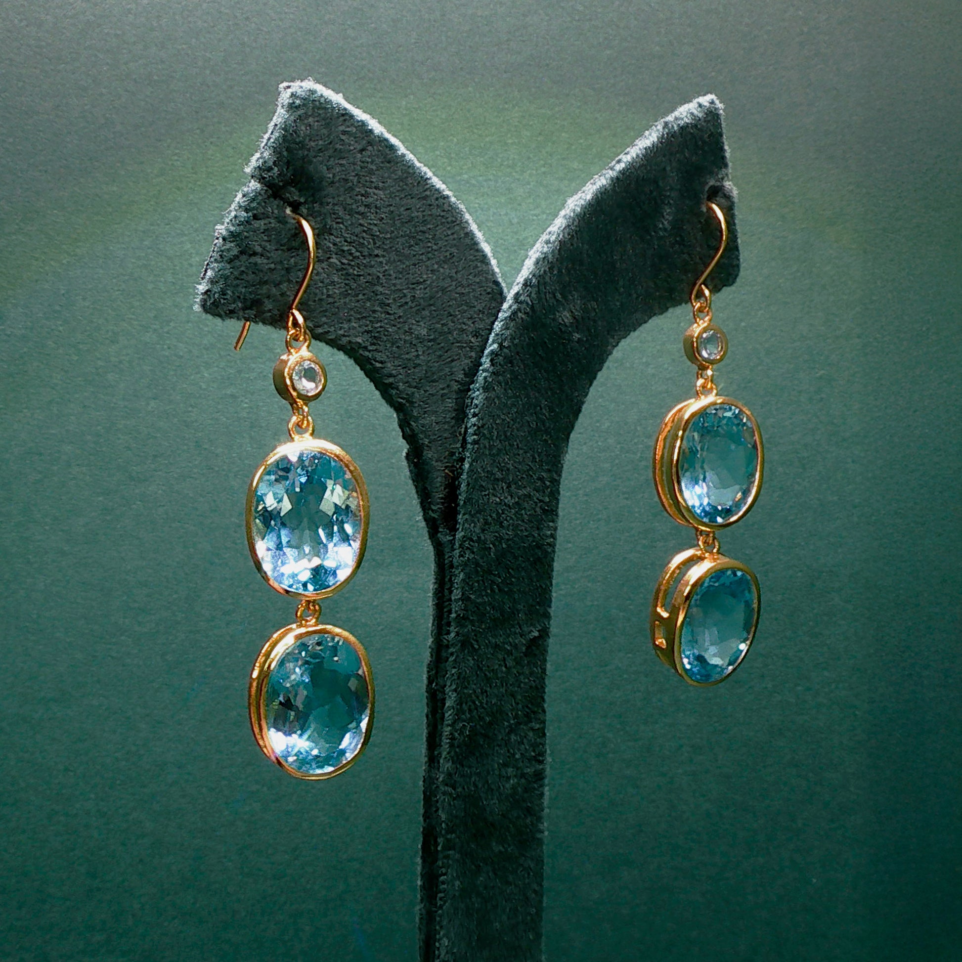 Pair of earrings with blue gemstones on a green stand

