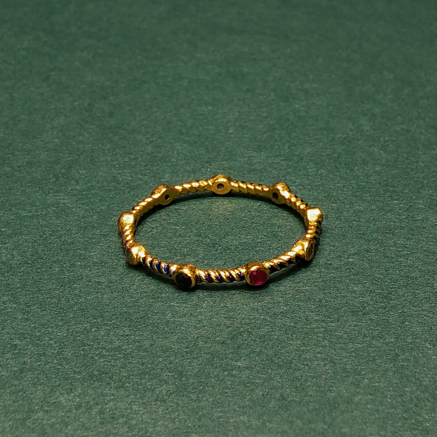 Gold ring with embedded gemstones on a green background