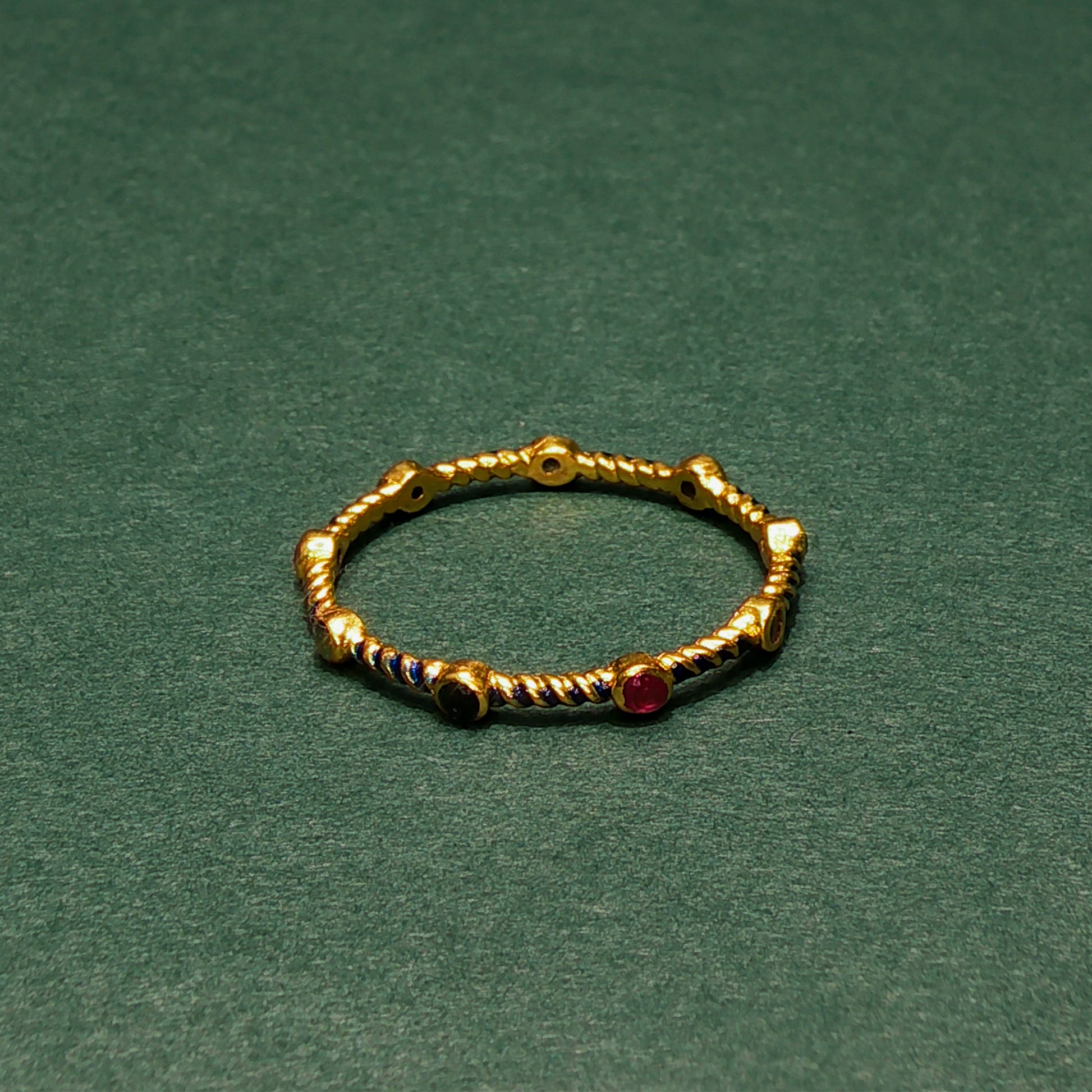Gold ring with embedded gemstones on a green background