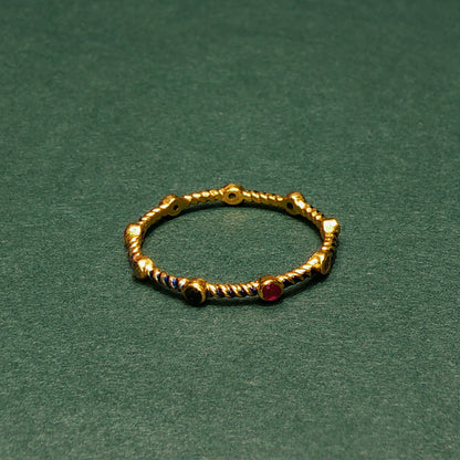 Gold ring with embedded gemstones on a green background