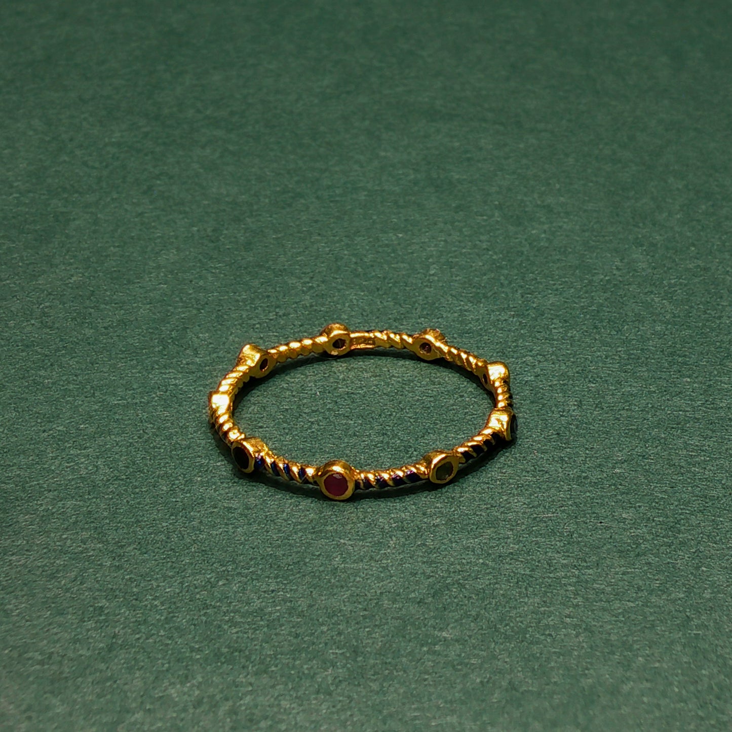 Gold ring with red gemstones on a green background