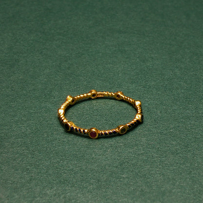 Gold ring with red gemstones on a green background