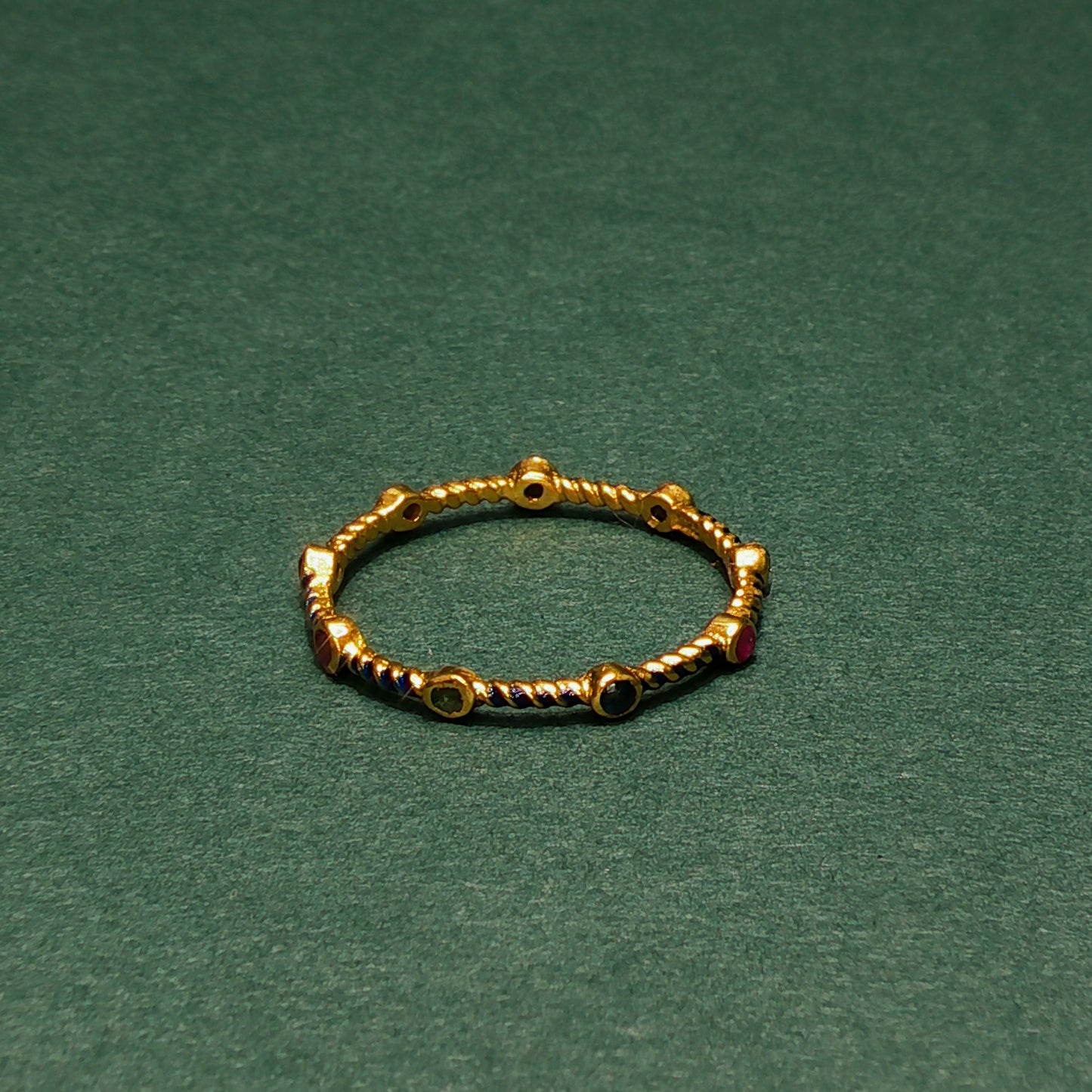 Gold ring with small gemstones on a green background