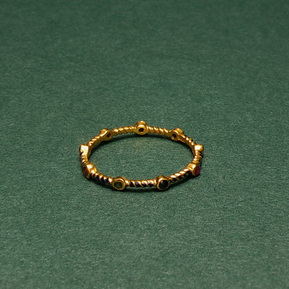 Gold ring with small gemstones on a green background