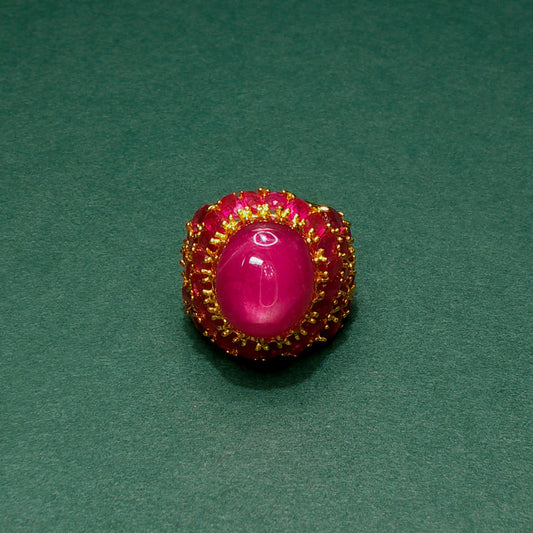 Pink gemstone ring with gold setting on a green background