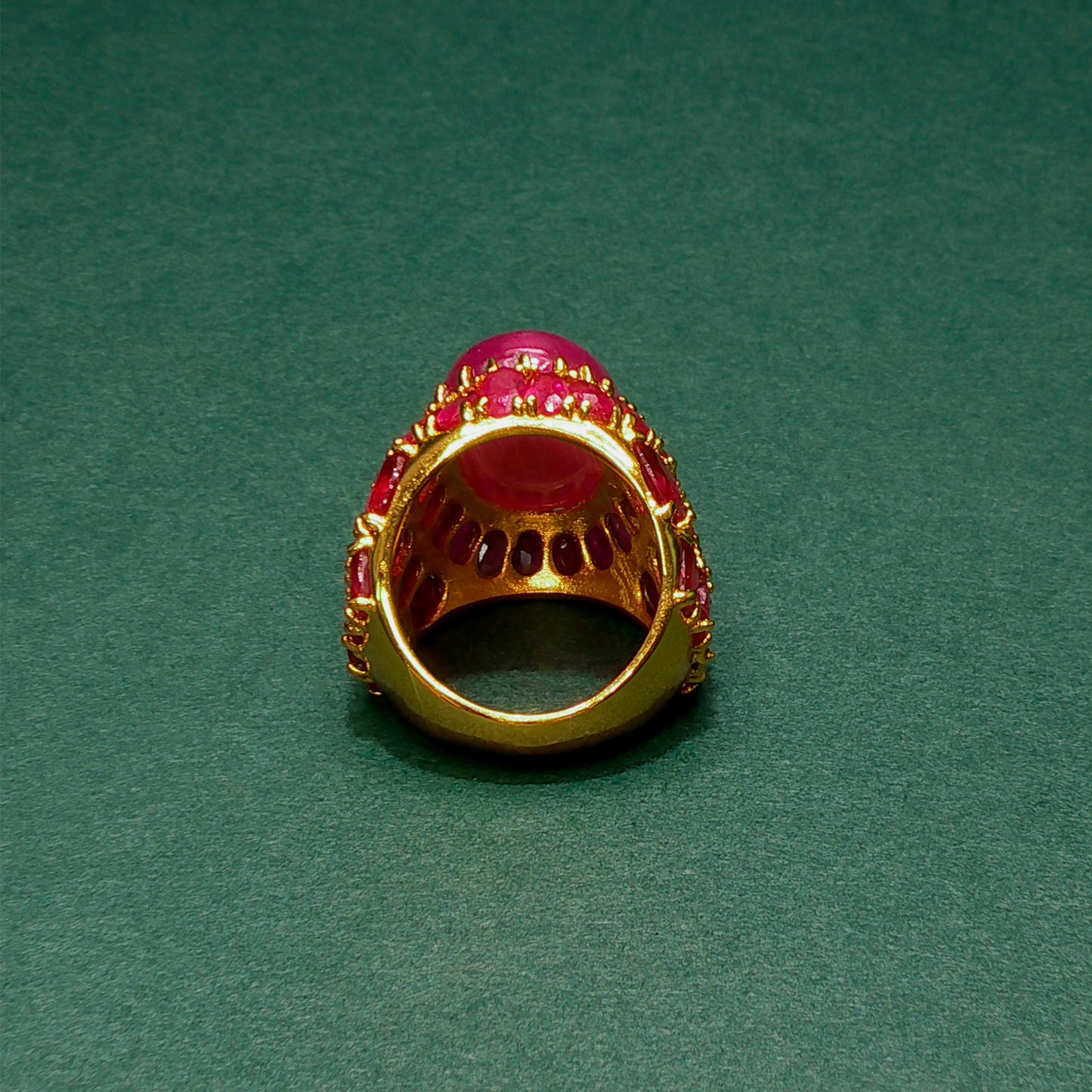 Gold ring with red gemstones on a green background