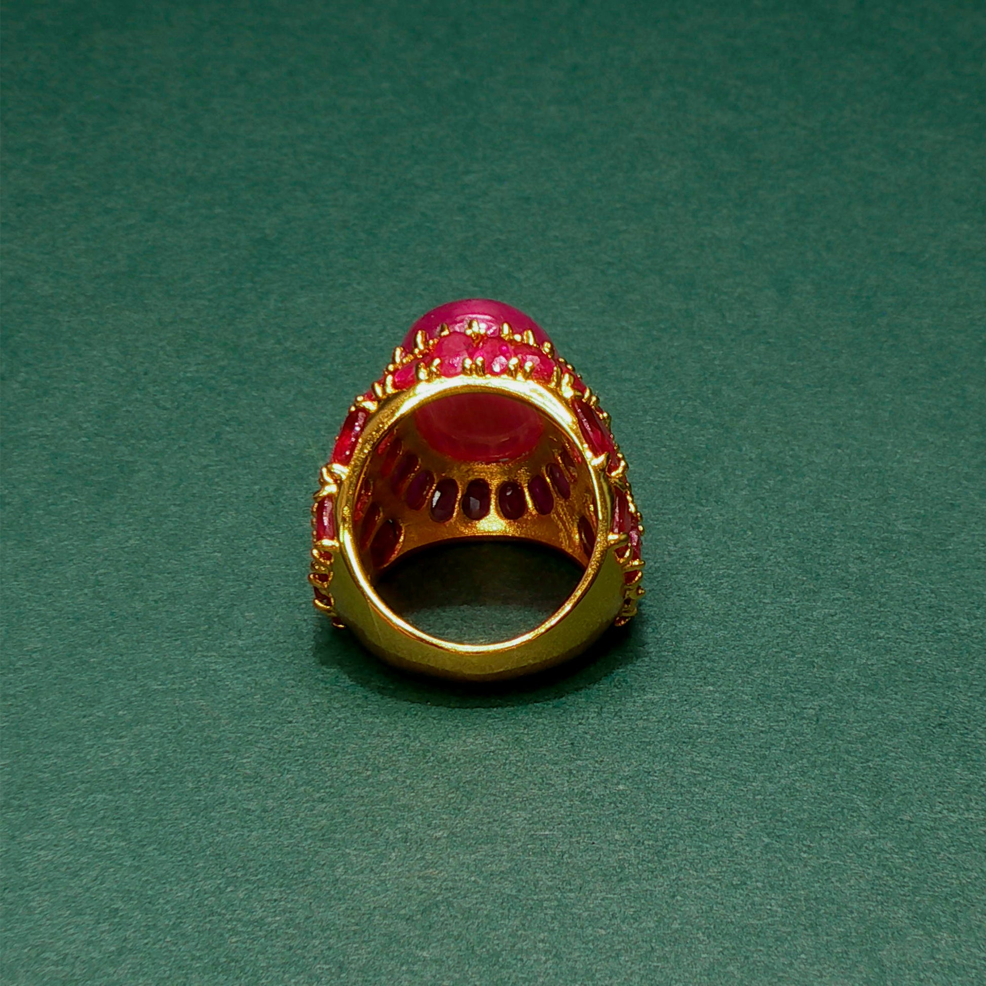 Gold ring with red gemstones on a green background