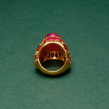 Gold ring with red gemstones on a green background