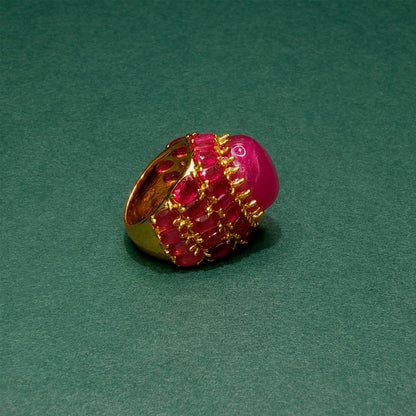 Pink gemstone ring with gold setting on a green background