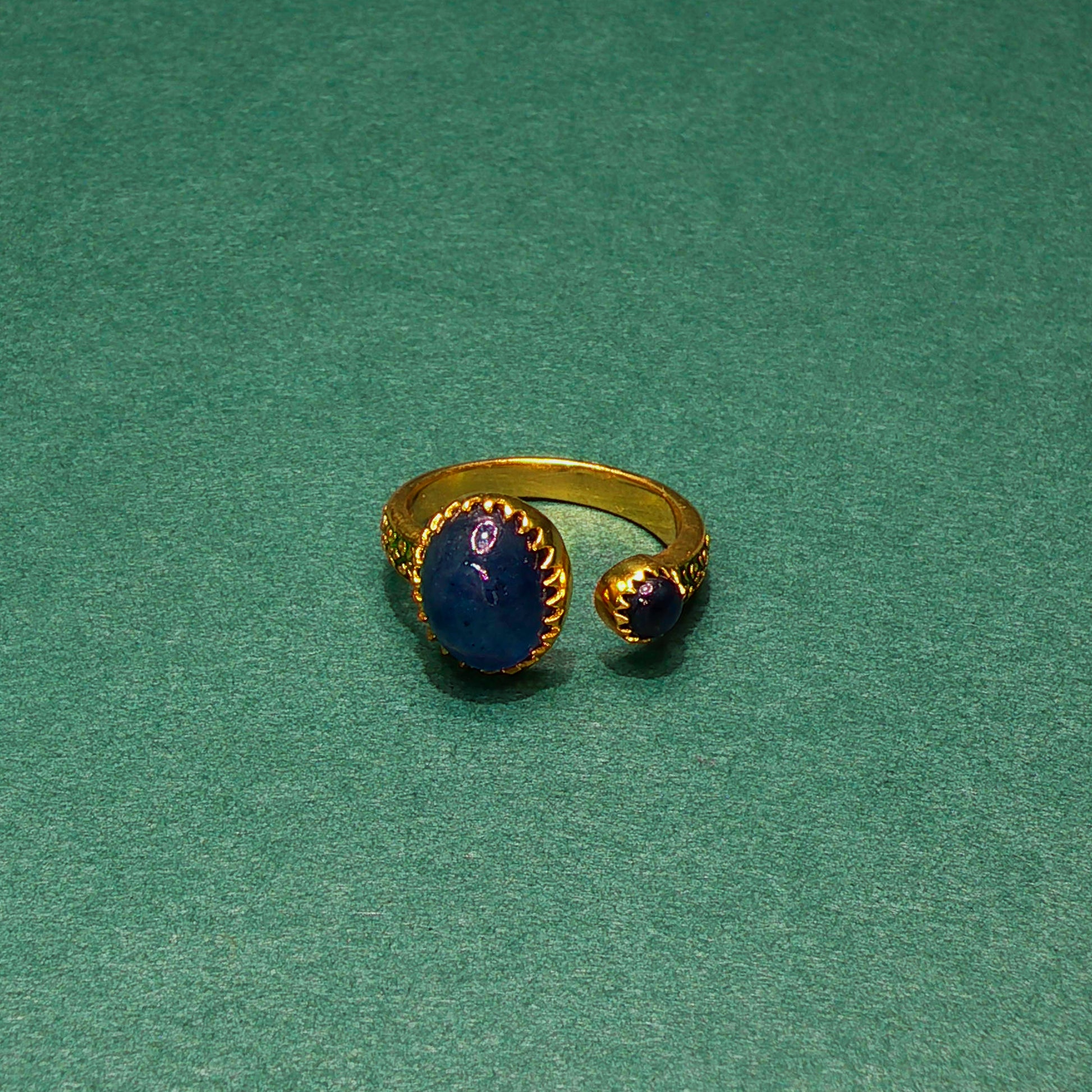 Gold ring with blue stone on a green background