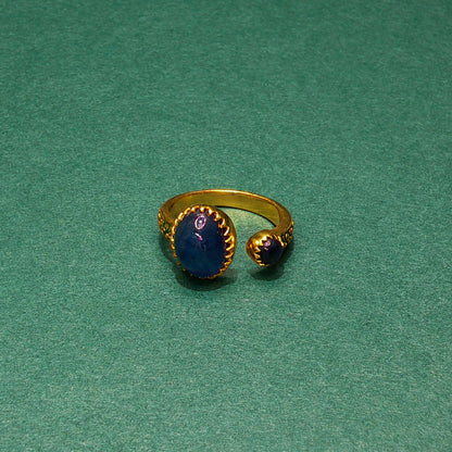 Gold ring with blue stone on a green background