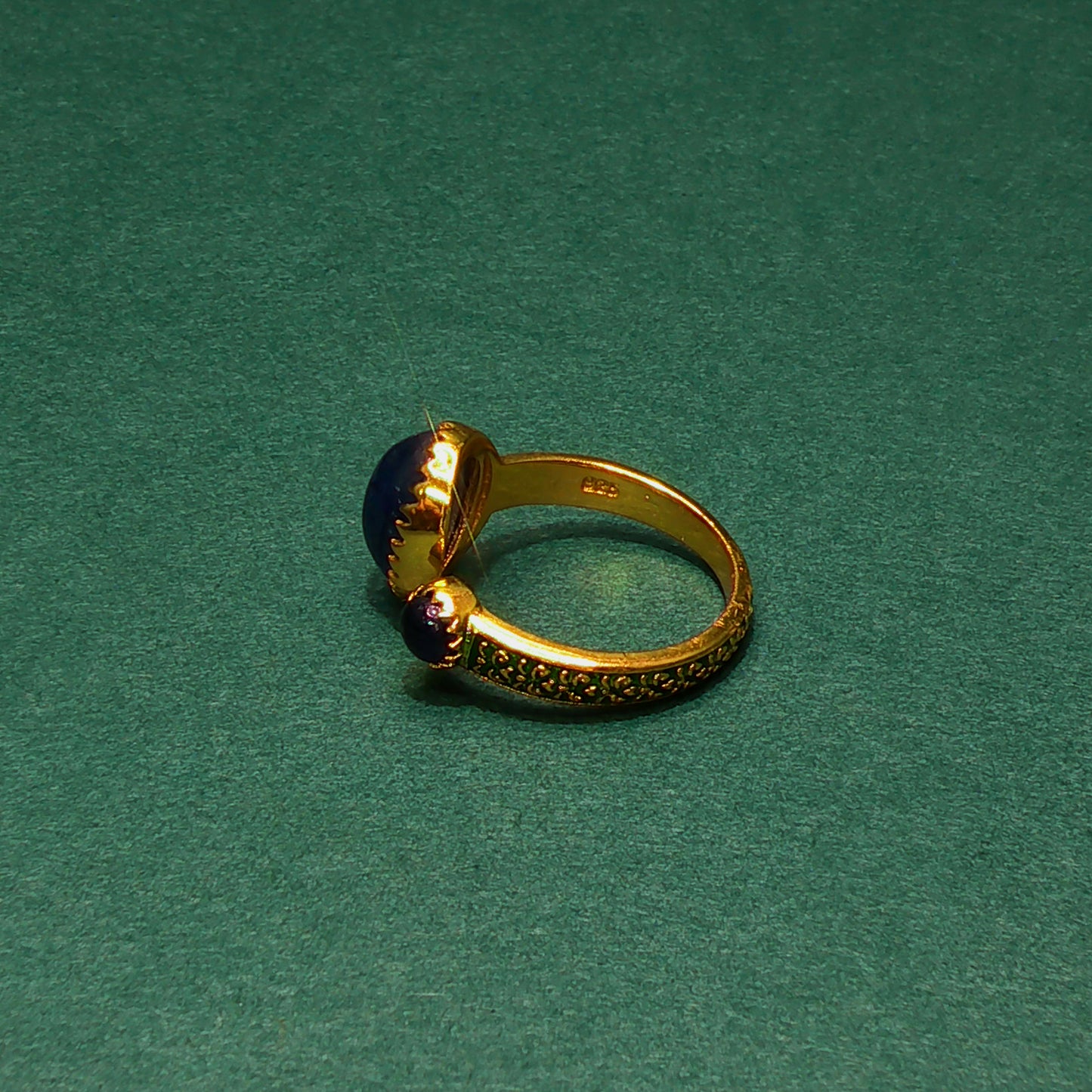 Gold ear cuff with a blue stone on a green background