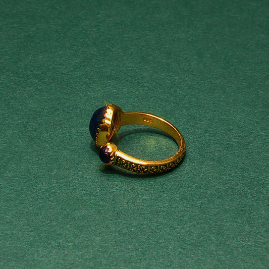 Gold ear cuff with a blue stone on a green background