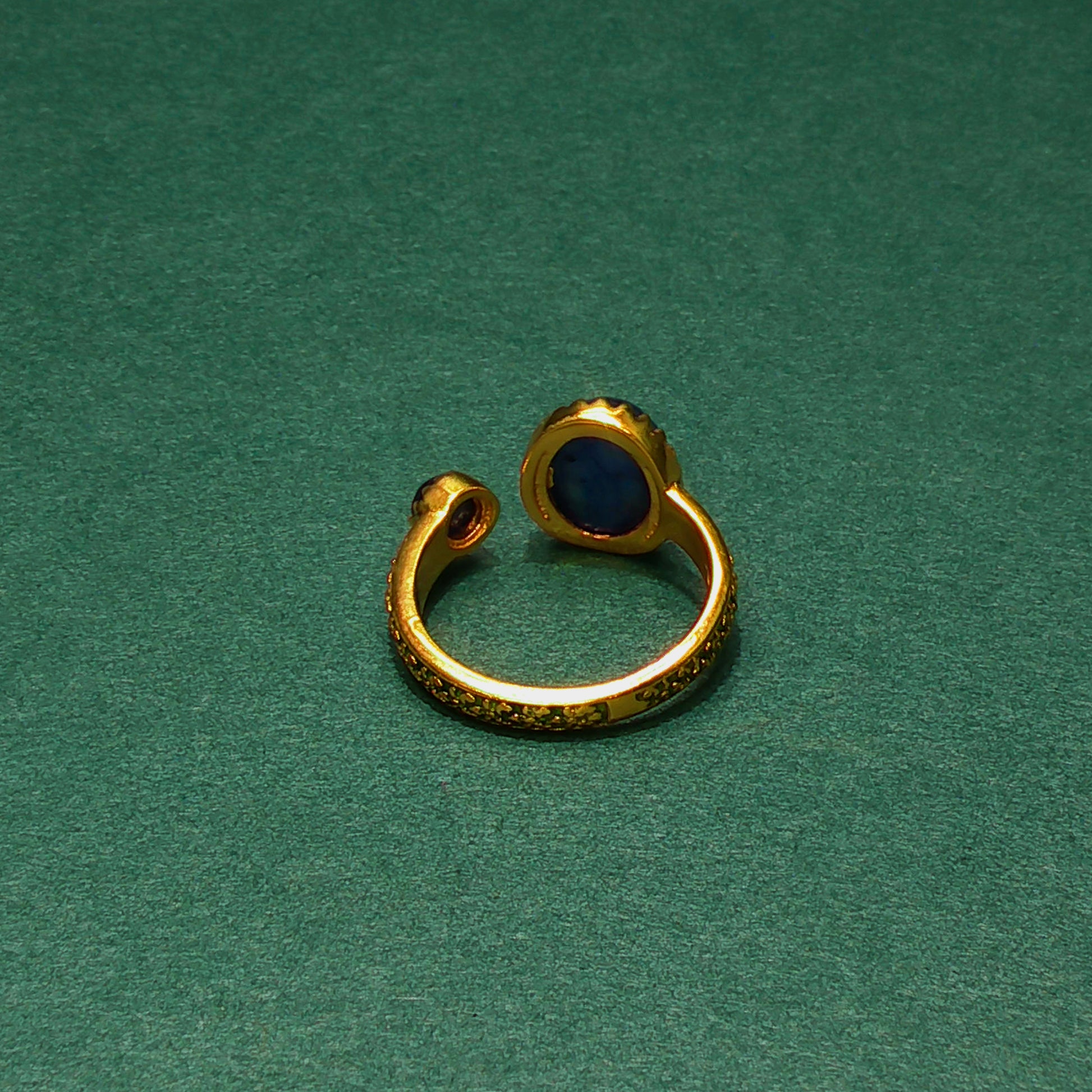 Gold ear cuff with a blue stone on a green background