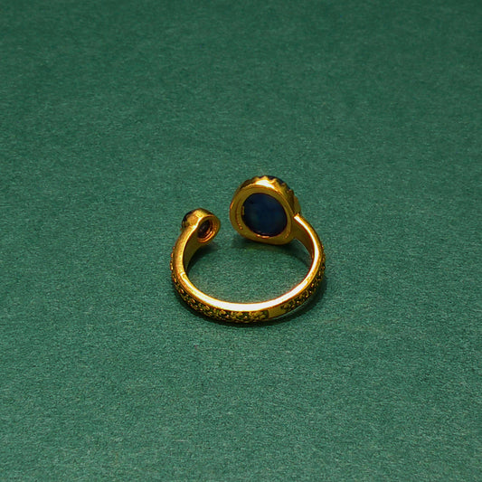 Gold ear cuff with a blue stone on a green background