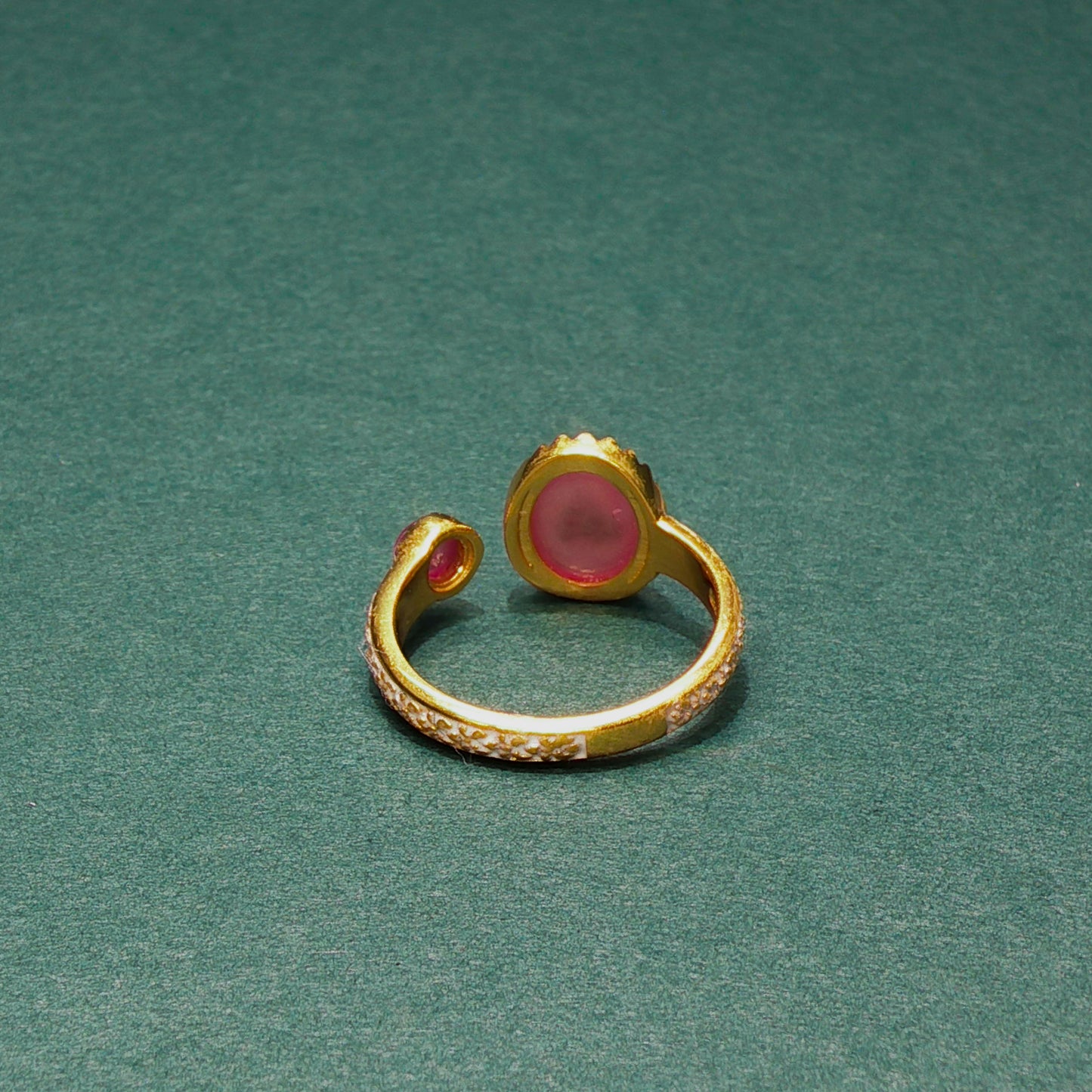 Gold ring with a pink gemstone on a green background