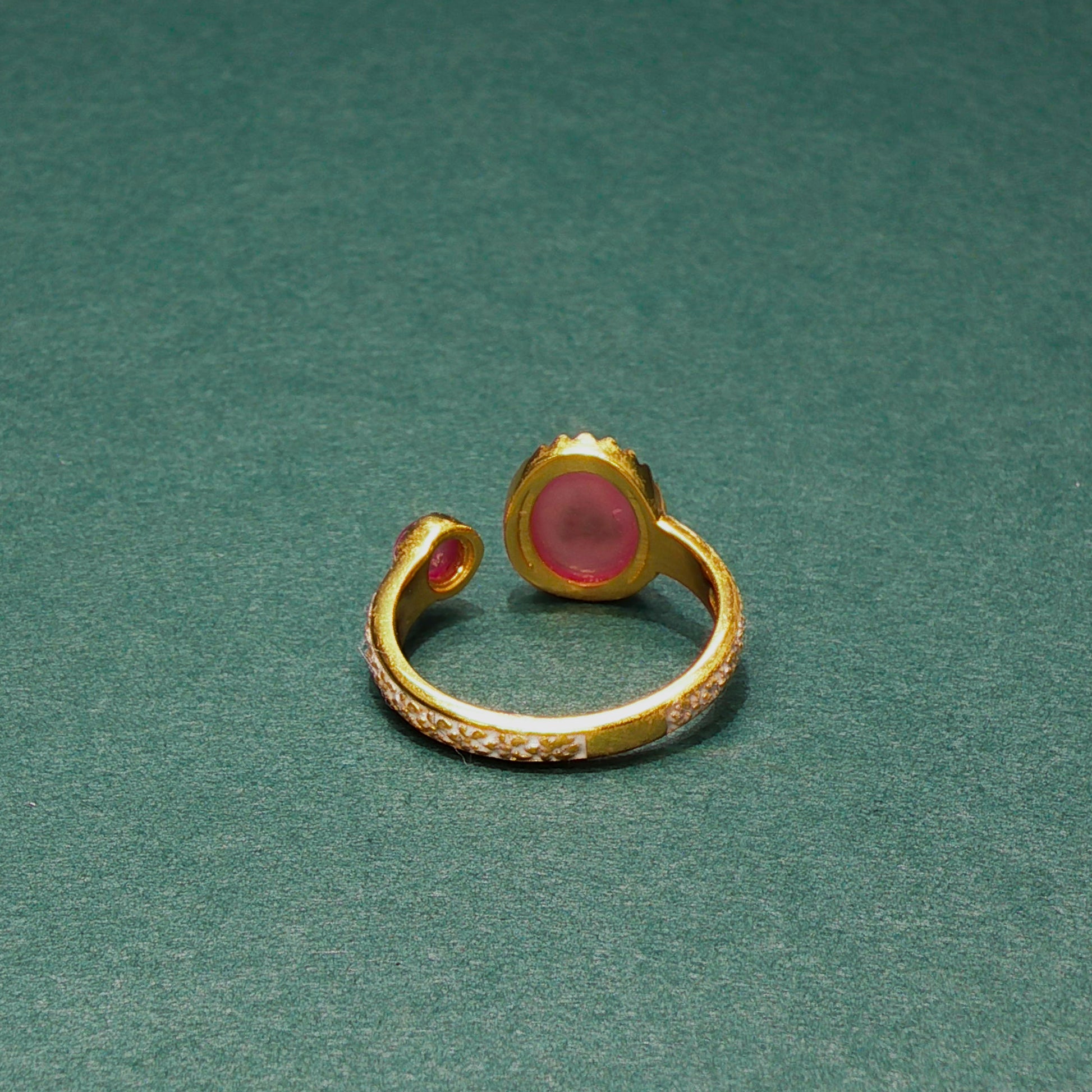 Gold ring with a pink gemstone on a green background