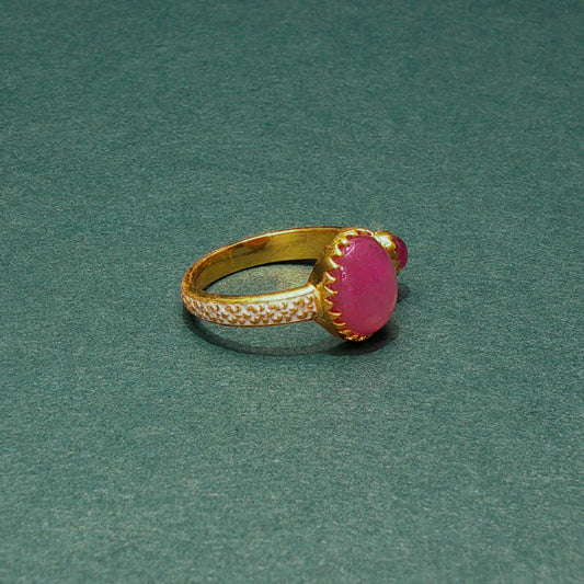 Gold ring with a pink gemstone on a green background