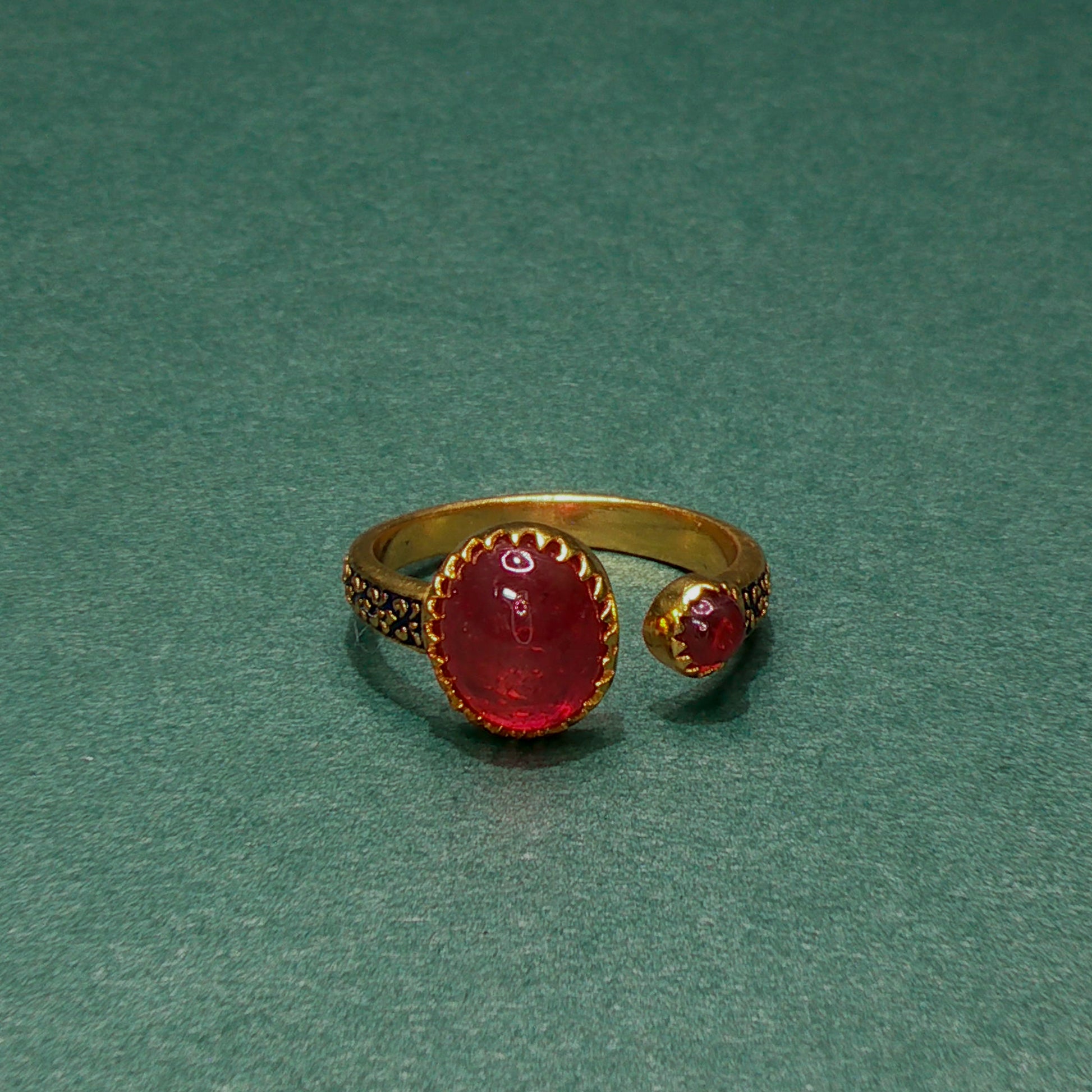 Gold ring with red gemstone on a green background