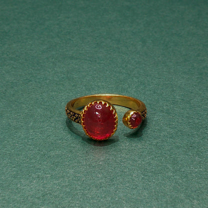 Gold ring with red gemstone on a green background