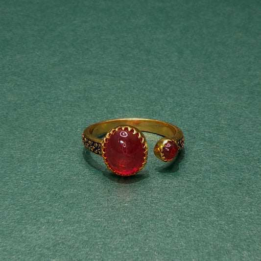 Gold ring with red gemstone on a green background