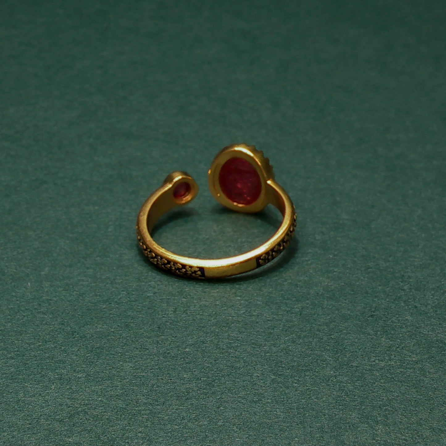 Gold ring with red gemstone on a green background