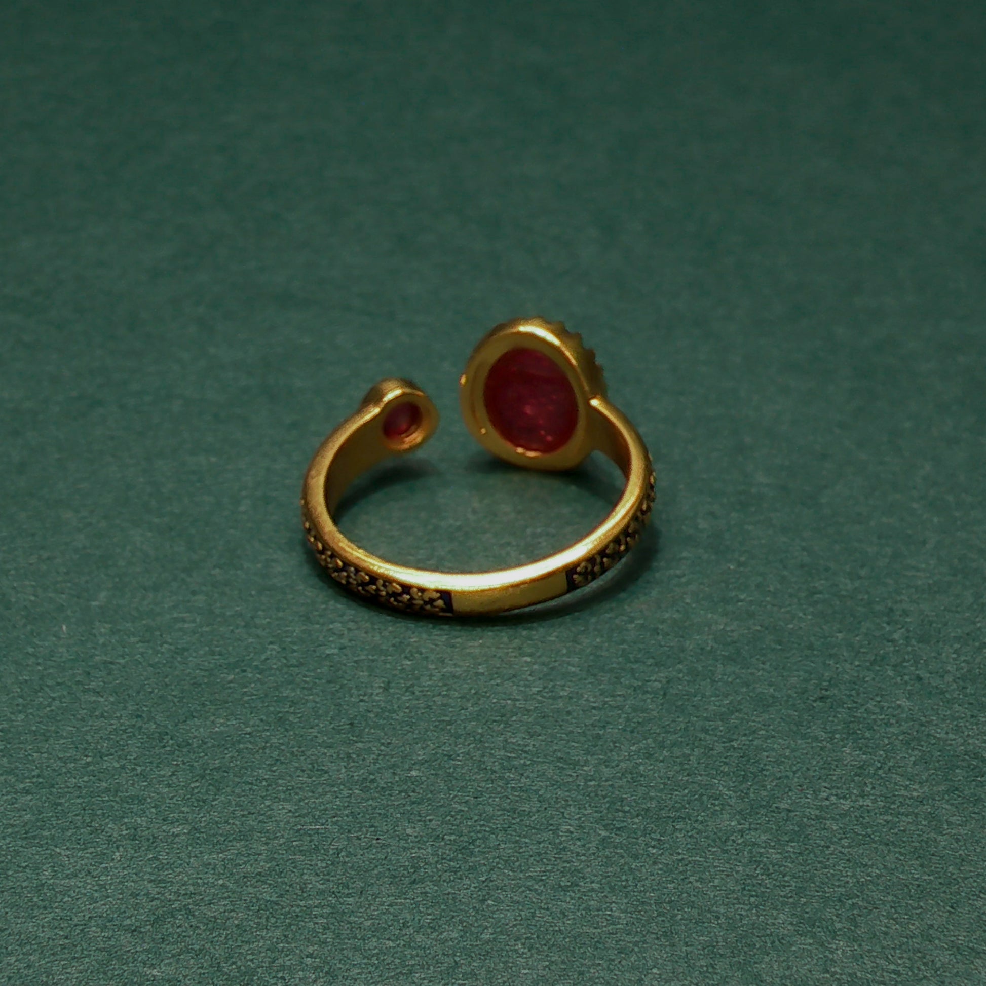 Gold ring with red gemstone on a green background