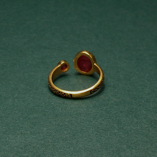 Gold ring with red gemstone on a green background