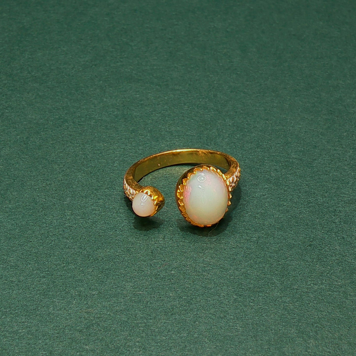 Gold ring with opal stones on a green background