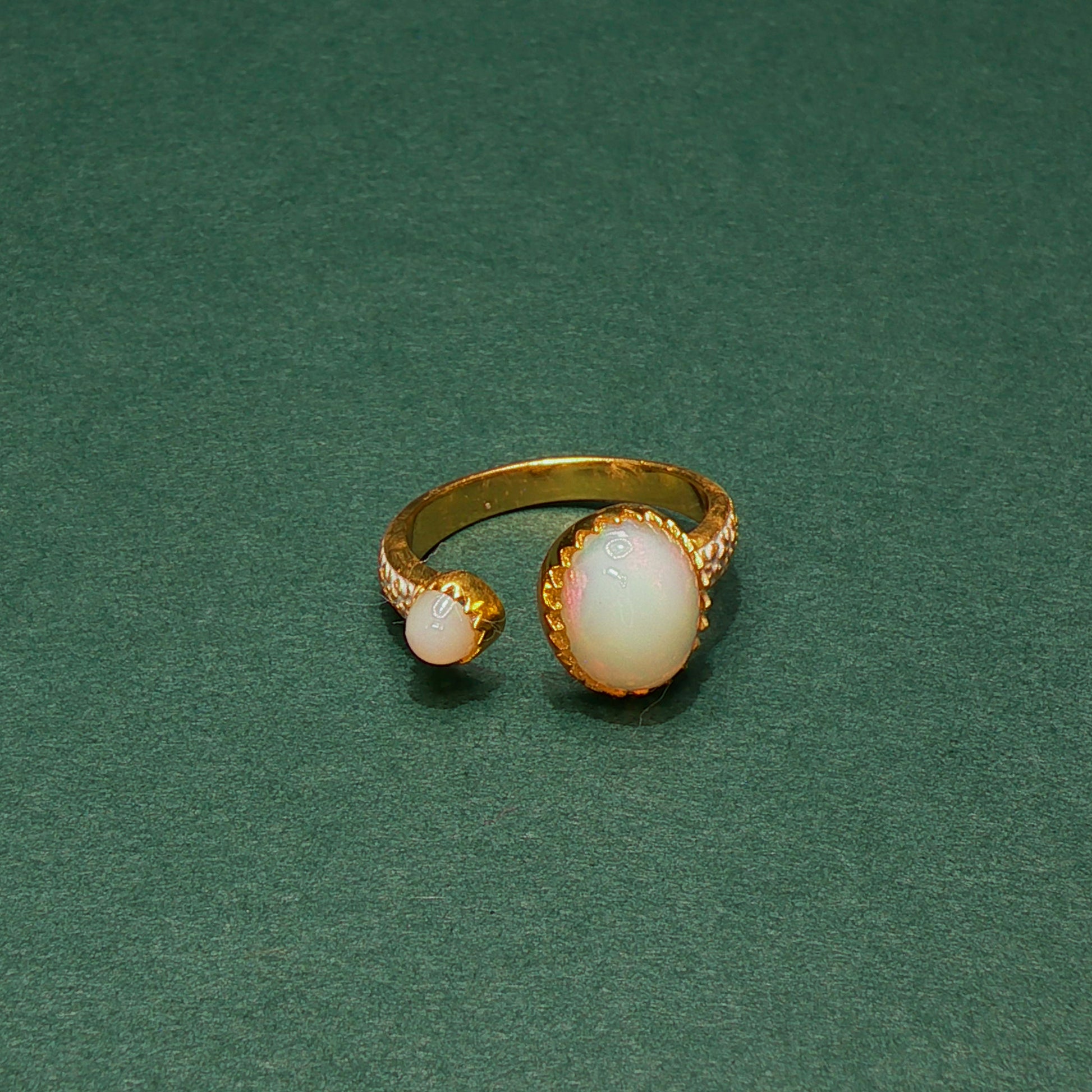 Gold ring with opal stones on a green background