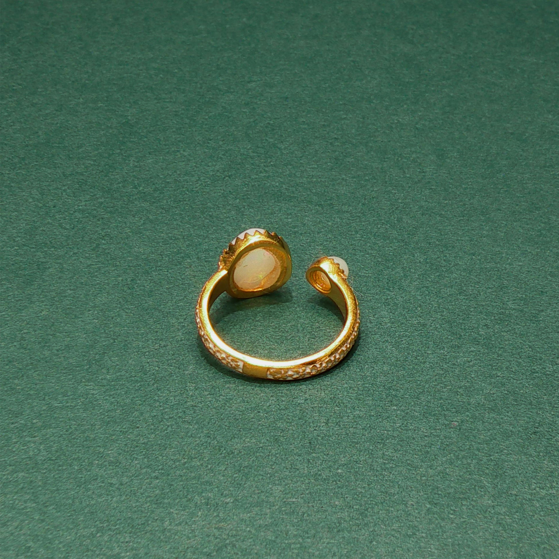 Gold ring with a central stone on a green background