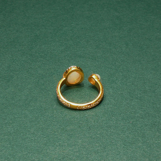 Gold ring with a central stone on a green background