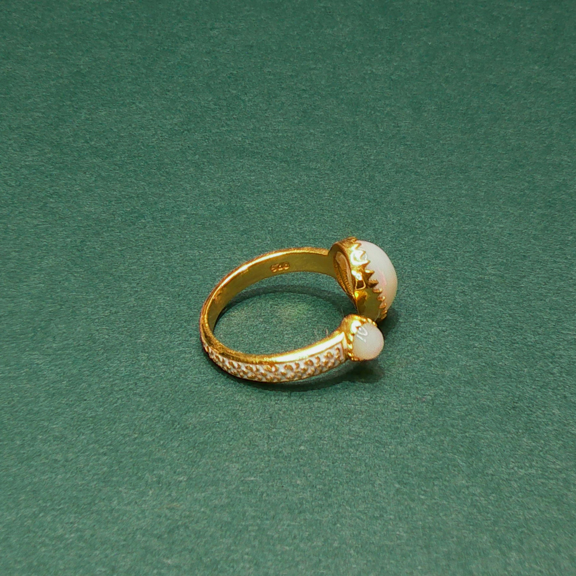 Gold ring with pearl accents on a green background