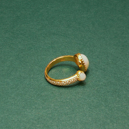 Gold ring with pearl accents on a green background